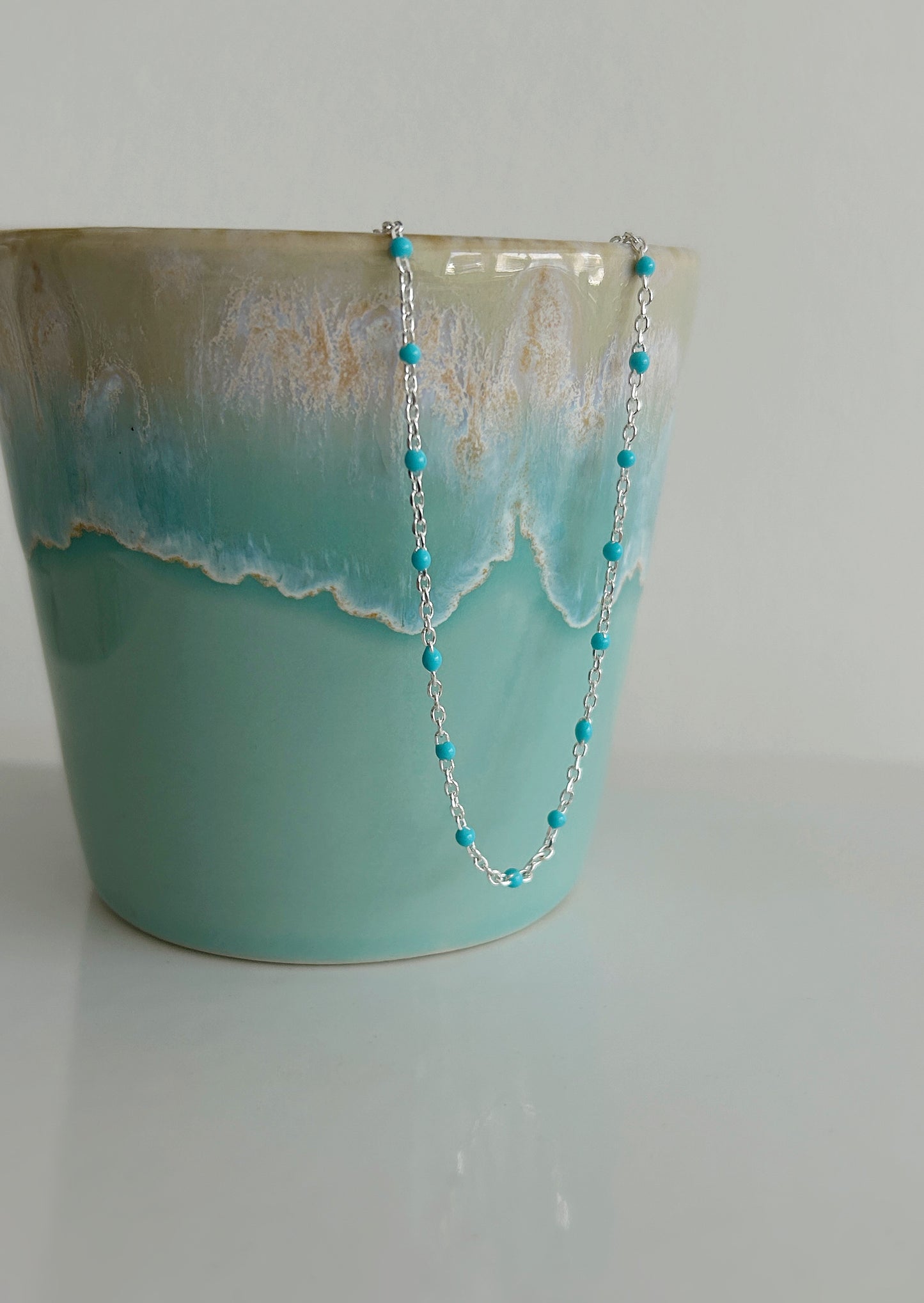 A delicate Gold filled or Sterling Silver flat cable chain necklace dotted with turquoise enamel beads, and finished off with a tiny Amazonite crystal bead at the clasp. 