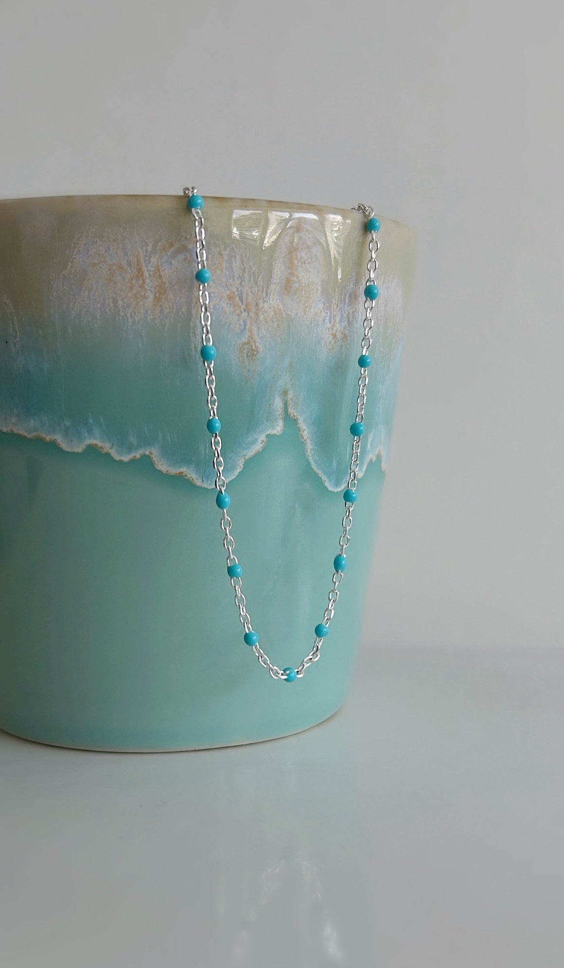A delicate Gold filled or Sterling Silver flat cable chain necklace dotted with turquoise enamel beads, and finished off with a tiny Amazonite crystal bead at the clasp. 