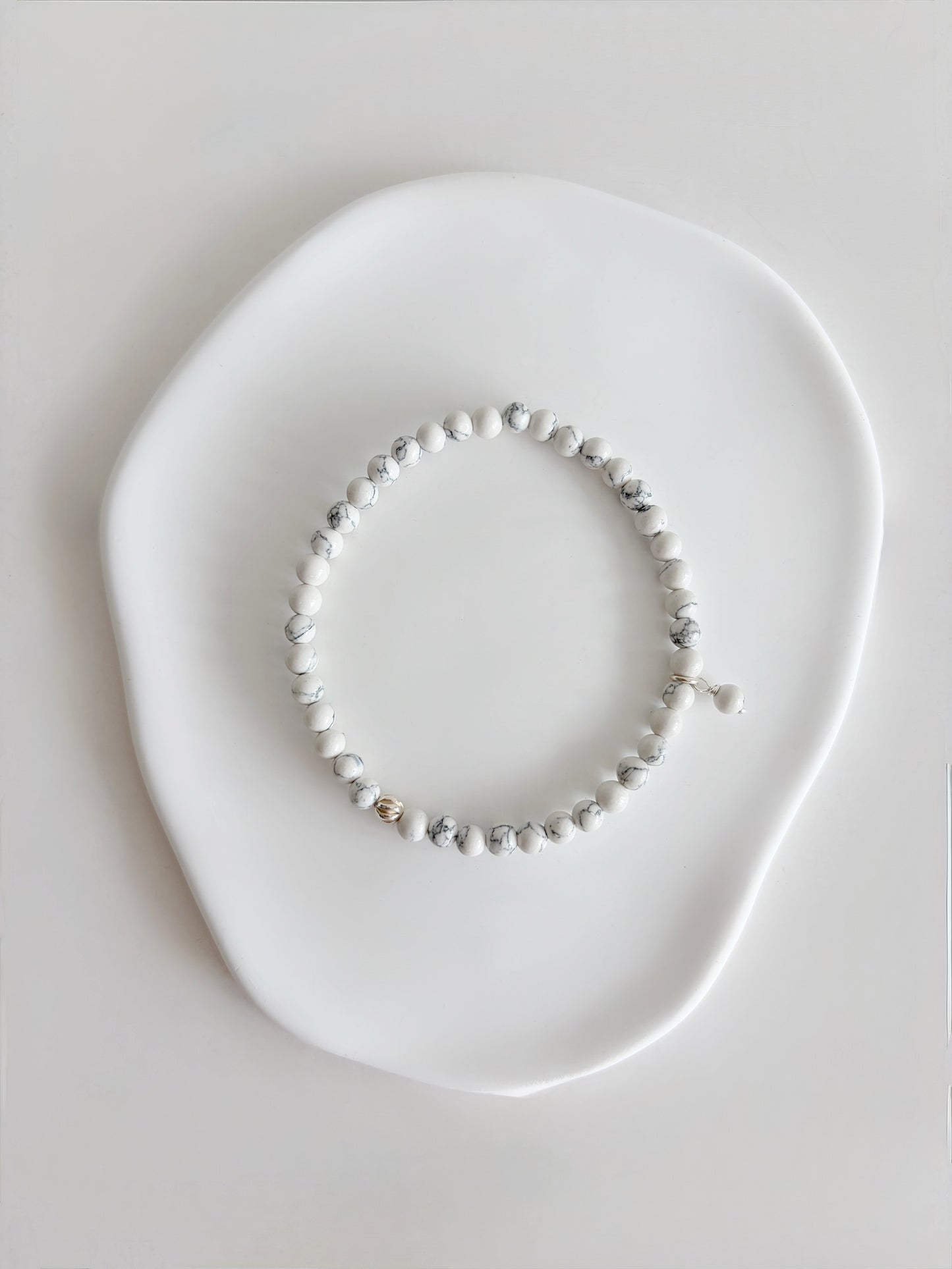 A beautiful semi precious beaded white Howlite stacking bracelet accented with a Sterling Silver twist engraved bead and a Howlite dangle bead, hand threaded on a durable stretch cord.