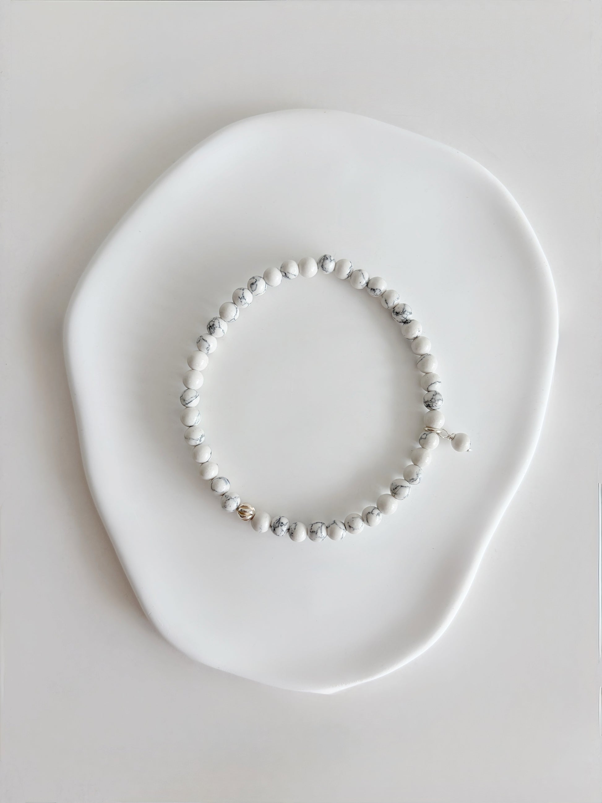 A beautiful semi precious beaded white Howlite stacking bracelet accented with a Sterling Silver twist engraved bead and a Howlite dangle bead, hand threaded on a durable stretch cord.