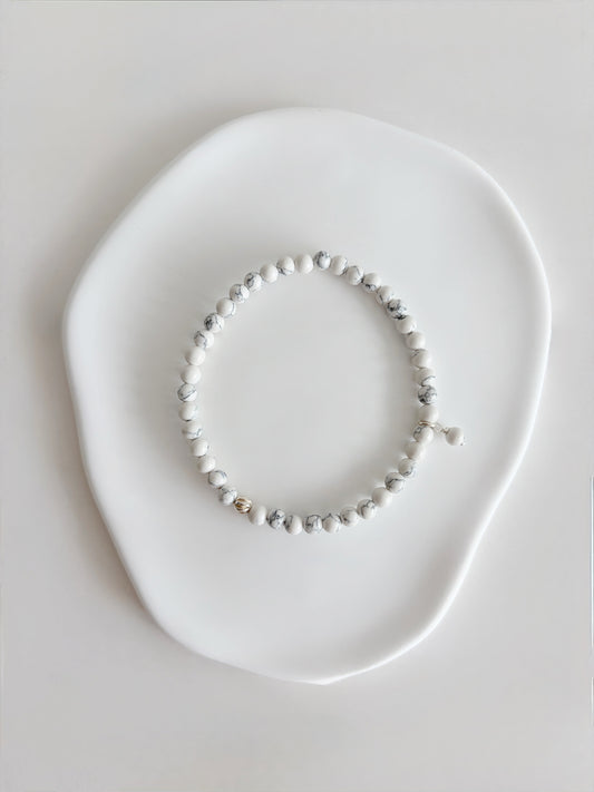 A beautiful semi precious beaded white Howlite stacking bracelet accented with a Sterling Silver twist engraved bead and a Howlite dangle bead, hand threaded on a durable stretch cord.